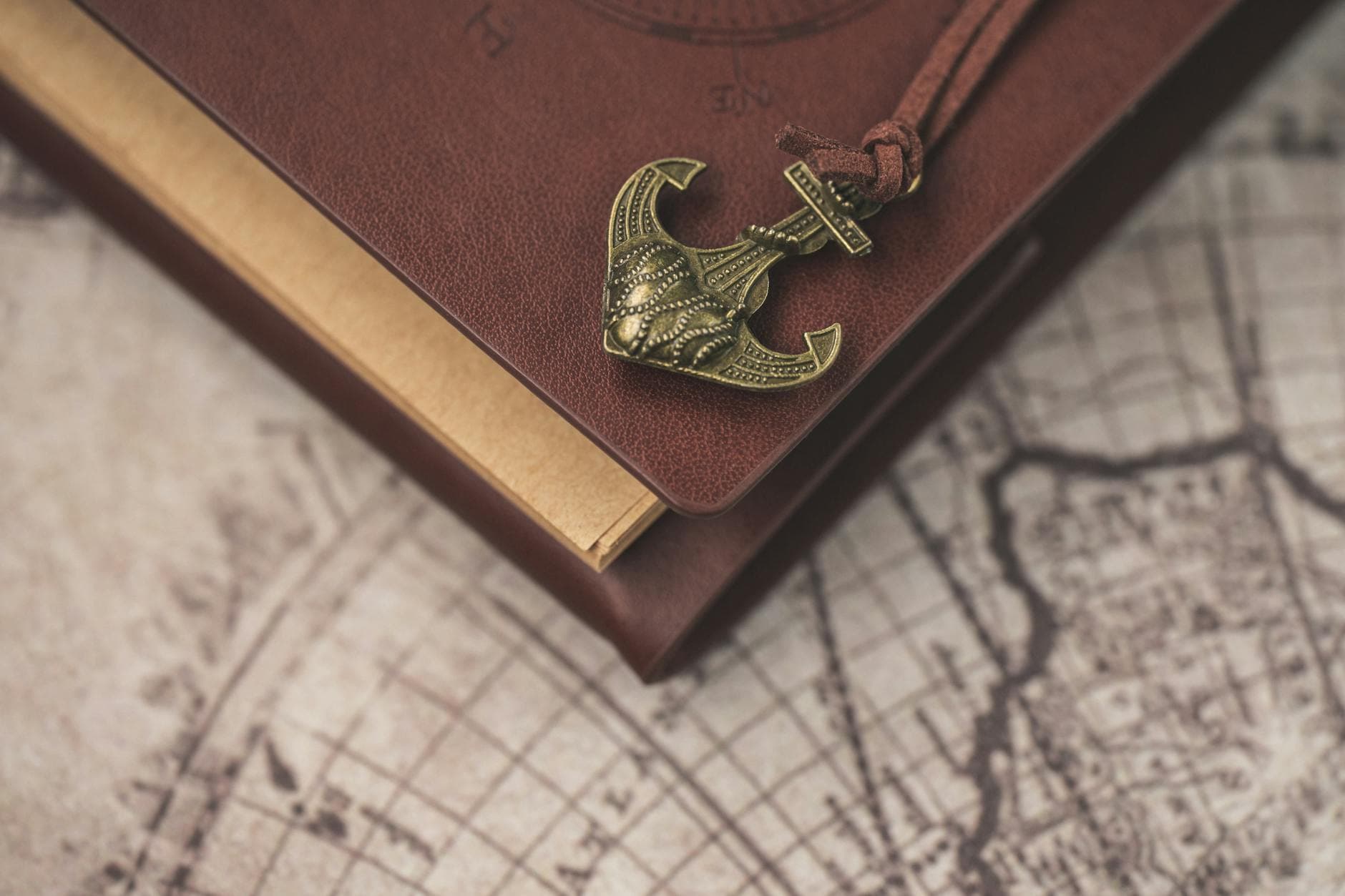 A vintage notebook with an anchor ornament on an old map