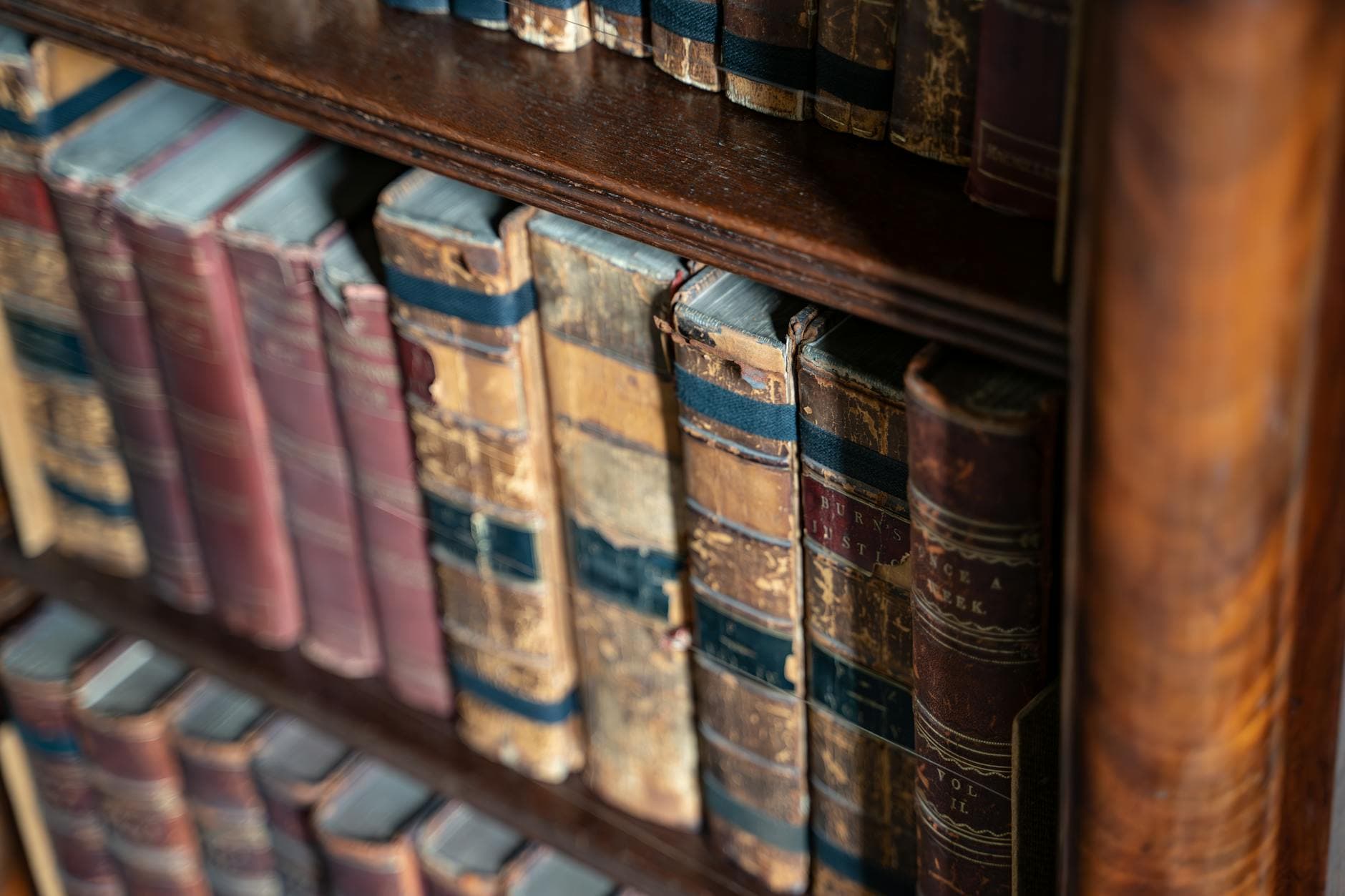 Vintage leather-bound books on rustic wooden shelves