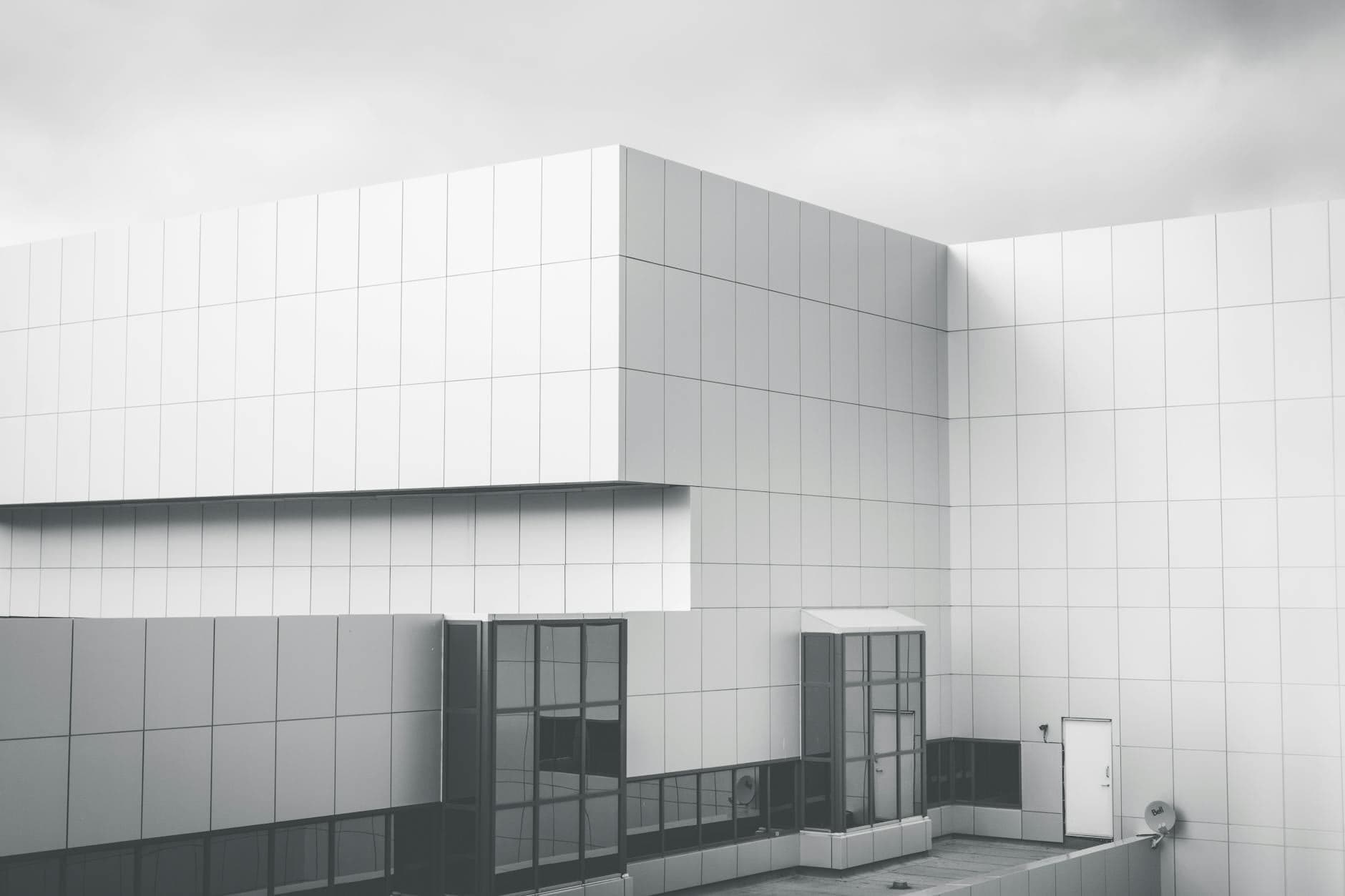 Minimalist white panel facade against a cloudy sky